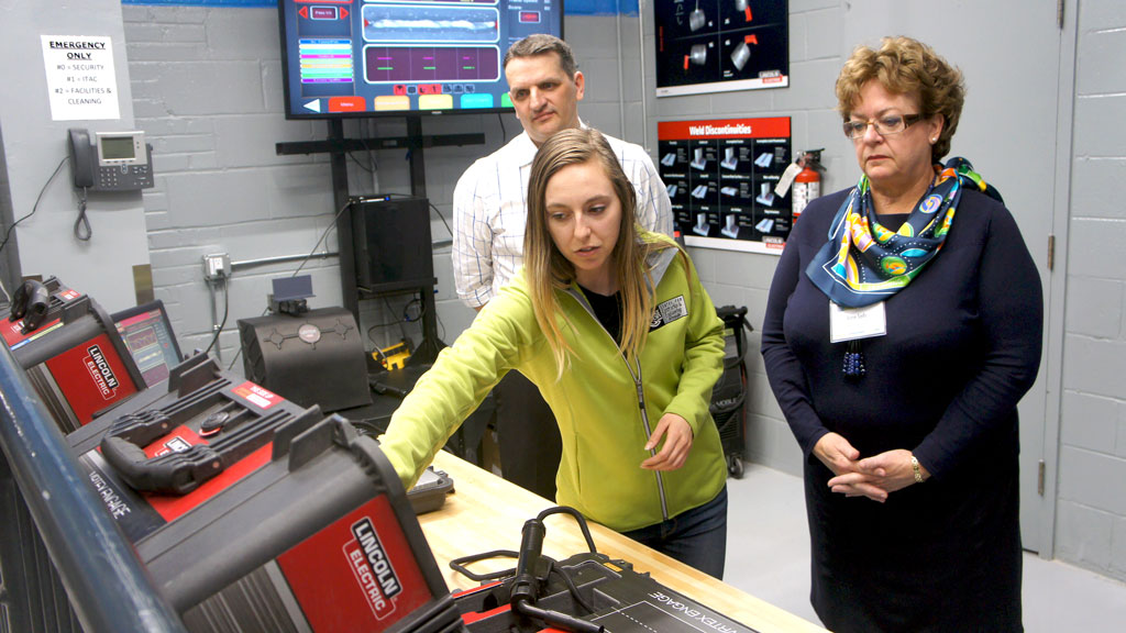 The grand opening for the new Smart Welding Lab at George Brown College features virtual welding equipment where students can practise their skills. Pictured, George Brown College president Anne Sado (right) learns how the machine works before testing it out.