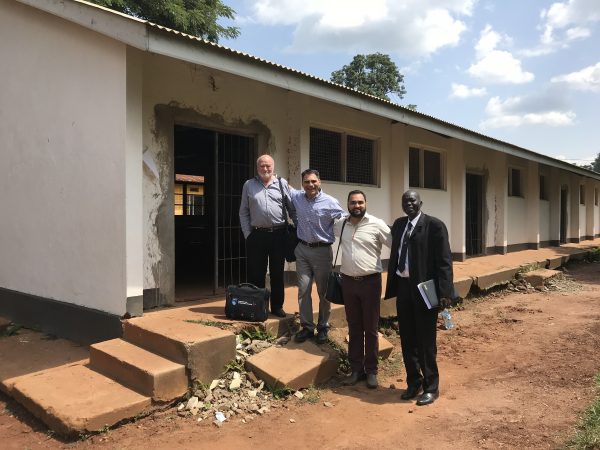 NAIT representatives Dr. Dave Rea, Ignacio Garcia and Dalpreet Virdi stand with Uganda Technical College deputy principal Moses Obong in front of the building that, once refurbished, will house a road construction training program scheduled to take place from 2019 to 2021.