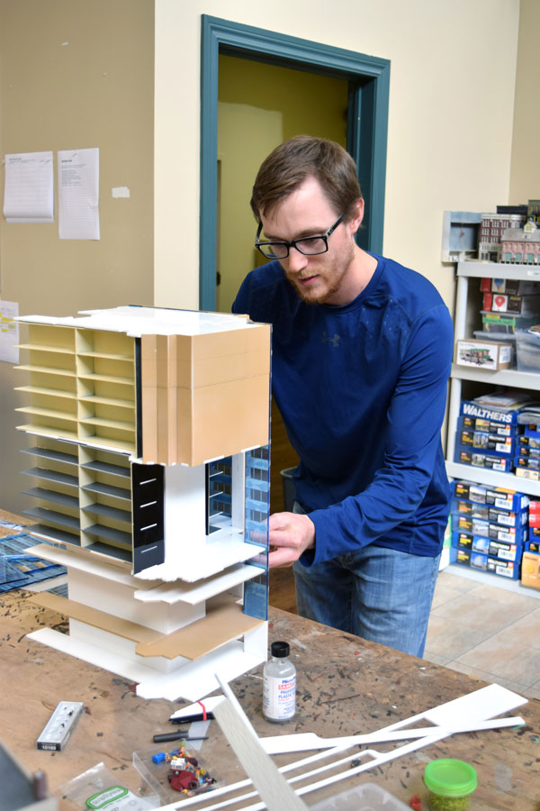 Onsite at the Britannia Road East workshop of Our Home & Miniature Land in Mississauga, modeller Mark Domanski examines a model of the Place du Portage building in Ottawa.