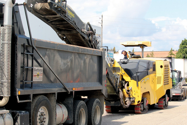 A Bomag BM 1200/35 cold planer milling the parking lot of a logistics company. Asphalt surfaces get milled and paved over regular, long intervals, of a decade or two, depending on their intensity of use.