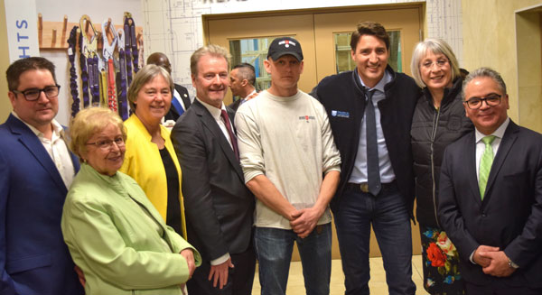 Prime Minister Justin Trudeau (third from right) received a College of Carpenters and Allied Trades jacket from Dimitri Berdnikov (fourth from right), a second-term apprentice who joined the union through the Helmets to Hardhats program, during a visit to the Carpenters’ training headquarters in Woodbridge, Ont. on March 22. Looking on were Mike Yorke (fifth from right), the director of public affairs for the Carpenters’ District Council of Ontario, Minister of Employment, Workforce Development and Labour Patty Hajdu (second from right) and others.