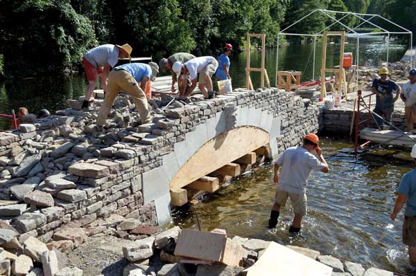 Wallers fill in the voids between the voussoirs with other stones on a bridge over the Tay River in Perth, Ont.