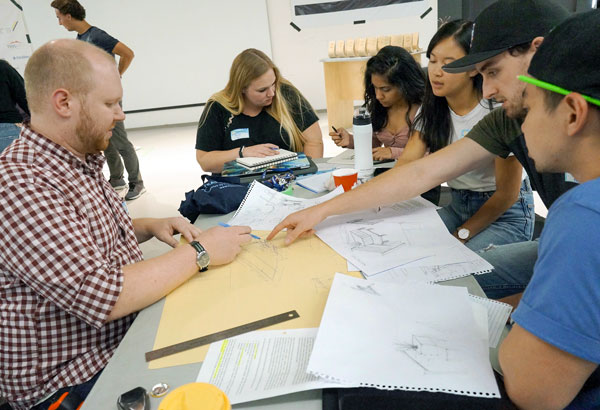 Andrew Jepson, Ryerson University Mentor (left) goes through design drawings with university participants at TimberFever 2019.